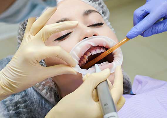 The image would likely depict a dental hygienist performing a cleaning to rectify dental issues at Glenn Smile Center.