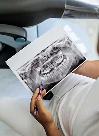 A woman sitting in a dentist's chair, examining dental x-rays with his caring Glenn Smile Center dentist.
